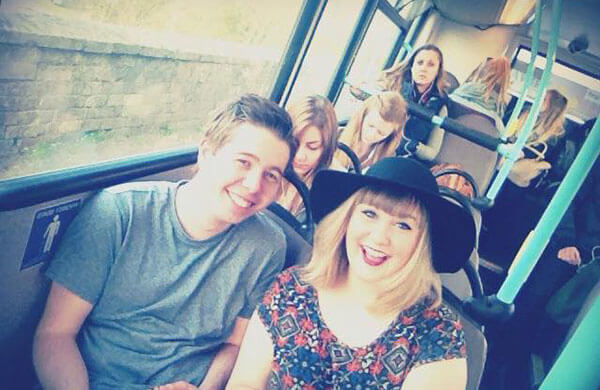 A selfie, taken by Laura, of Conor and her on the bus on their way to comedy society. They both have huge grins on their faces.